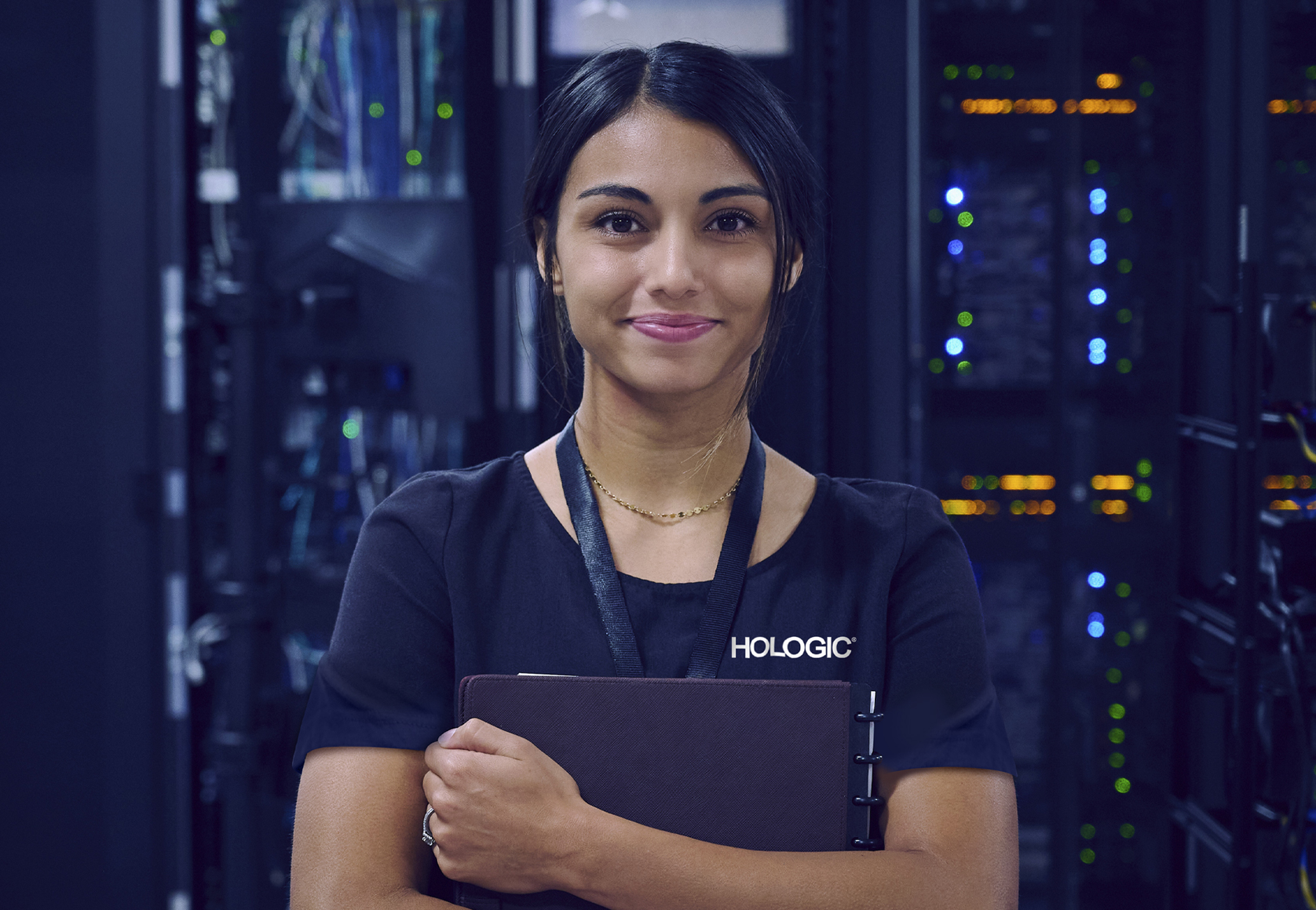 Hologic employee holding folder with infrastructure in background