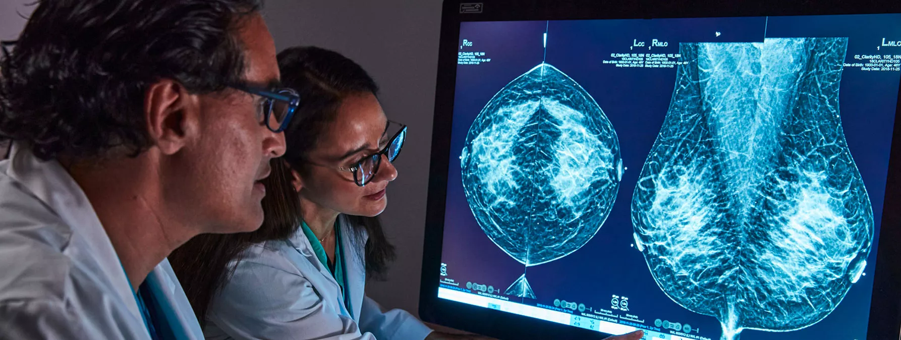 Healthcare professionals pointing to breast scan image on monitor