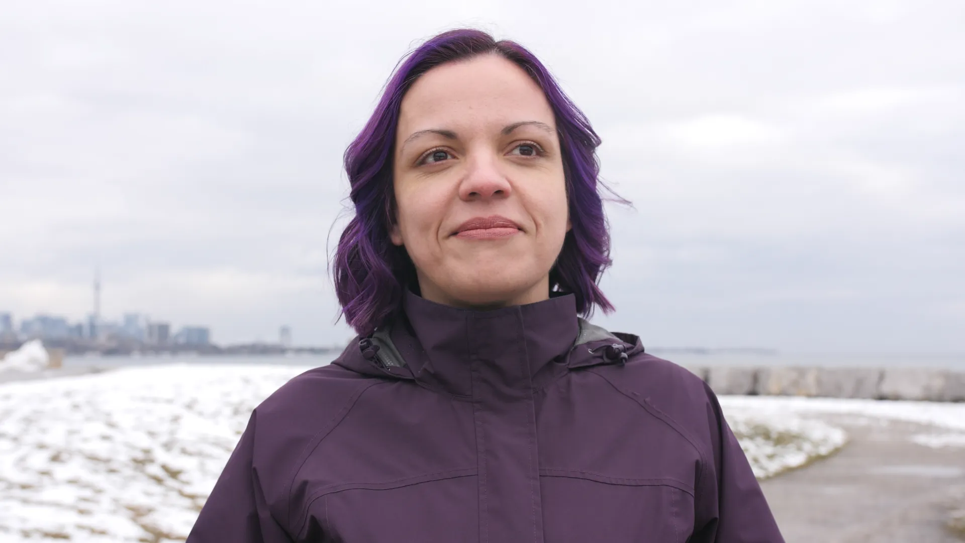 Femme dans un parc enneigé souriant et regardant au loin.