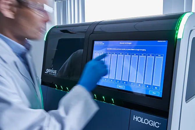 Professionnel de laboratoire utilisant l’écran tactile du système Genius Digital Diagnostics de Hologic